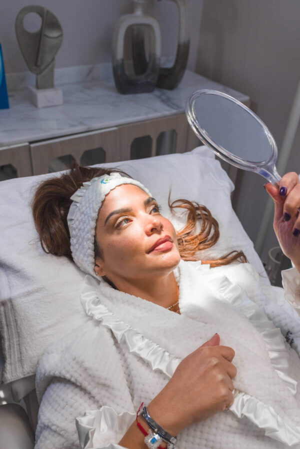 Mujer mirándose al espejo después de tratamiento Radiesse